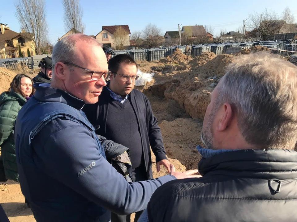 Simon Coveney is shown the site of mass graves where more than 50 bodies were found in Bucha (Department of Foreign Affairs/PA) (PA Media)