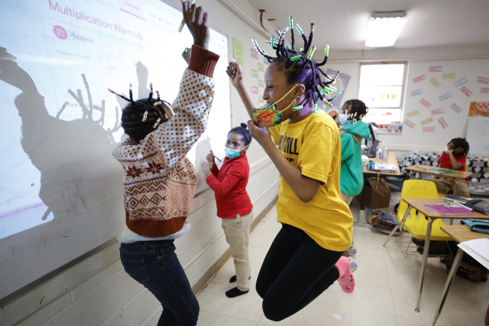 Niambi Cameron, 9, of Decatur, Ga., right, celebrates with classmates after answering a question during a math lesson at the Kilombo Academic and Cultural Institute, Tuesday, March 28, 2023, in Decatur, Ga. (AP Photo/Alex Slitz)