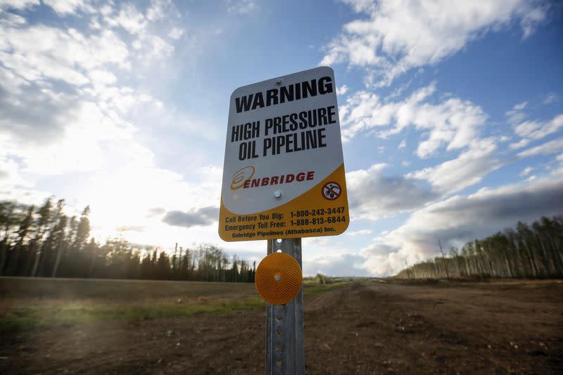 An Enbridge high pressure oil pipeline sign stands as smoke billows from the Fort McMurray in Kinosis