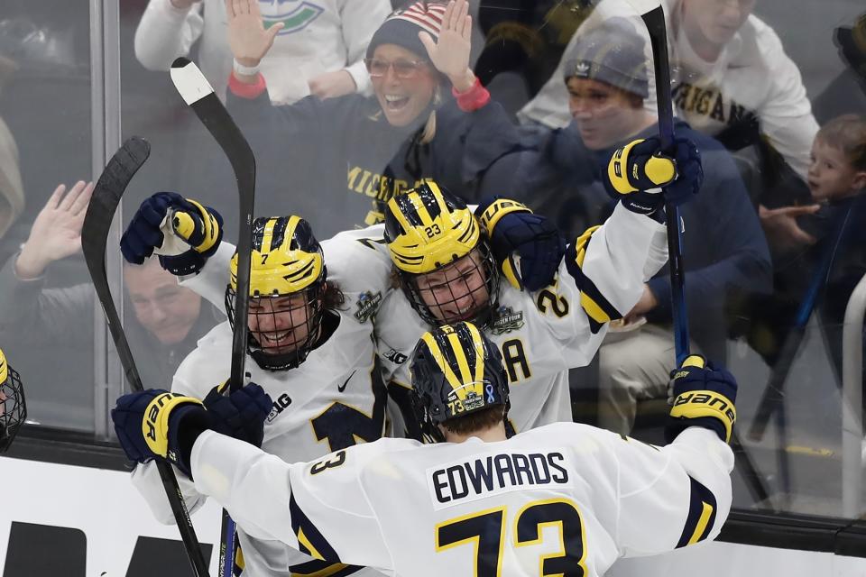 Michigan's Jimmy Lambert (23) celebrates his goal with Nick Blankenburg (7) and Ethan Edwards (73) during the second period of an NCAA men's Frozen Four semifinal hockey game against Denver, Thursday, April 7, 2022, in Boston. (AP Photo/Michael Dwyer)