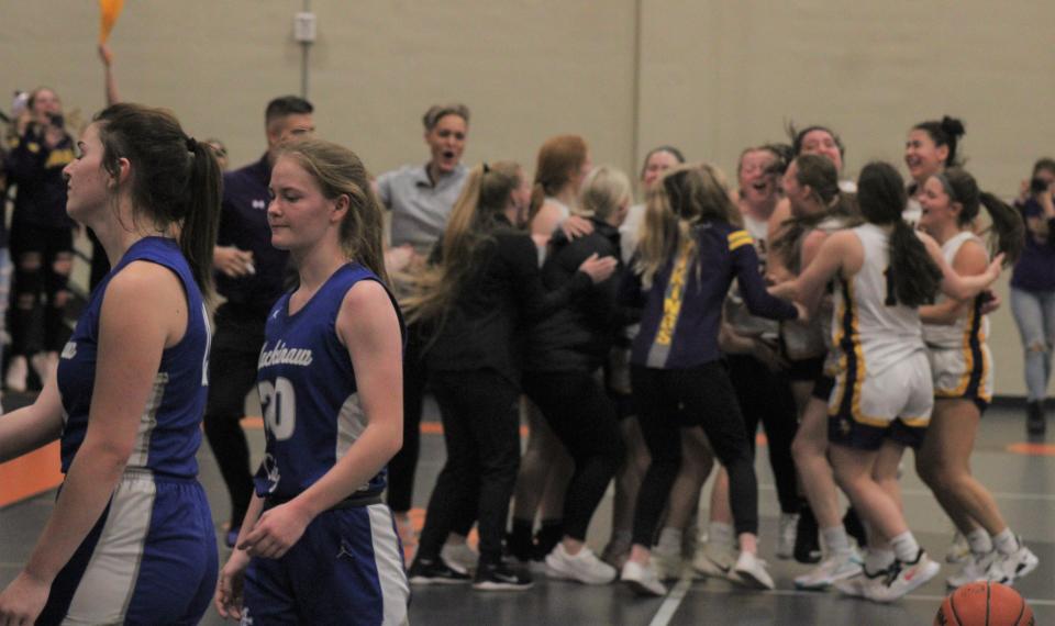 The Baraga girls basketball team celebrates a 40-36 victory while Mackinaw City players walk off the court following the conclusion of Tuesday's quarterfinal matchup in Munising.