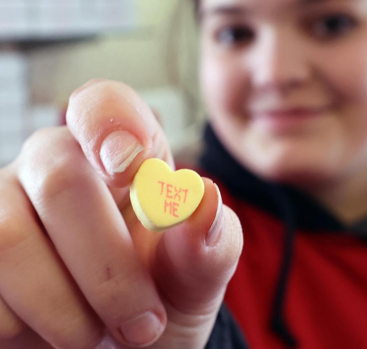 Molly Butts holds a heart-shaped conversation candy at Skinners Sugar House in East Bridgewater on Thursday, Jan. 18, 2024.