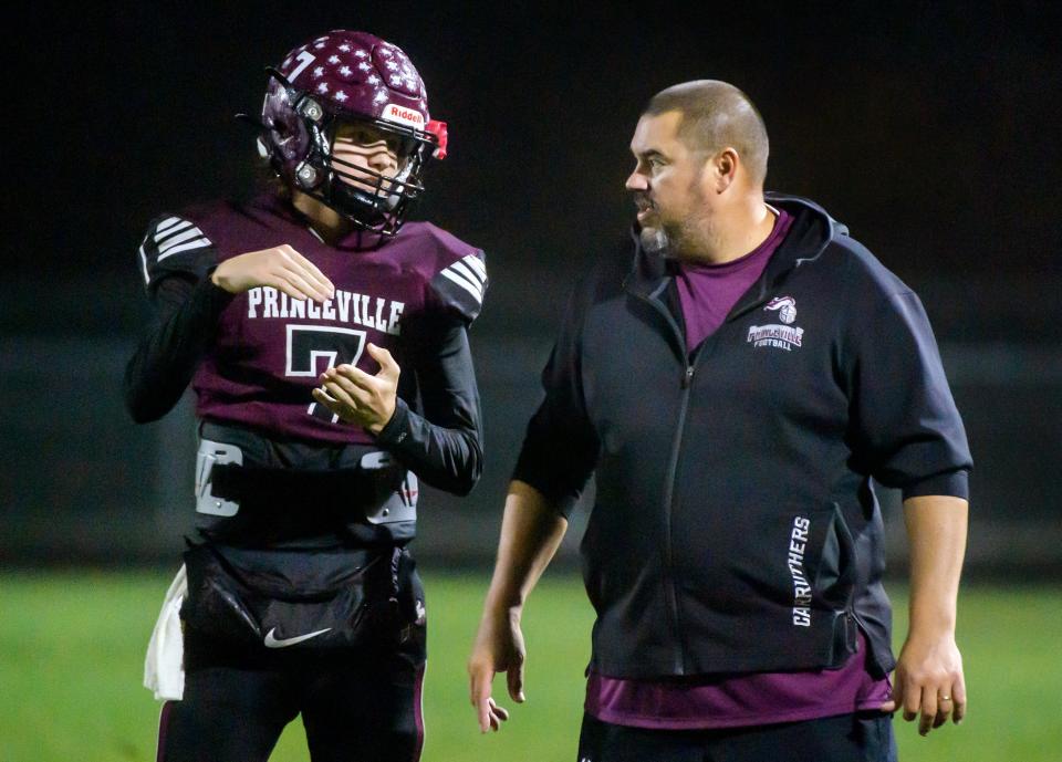 Princeville head coach Jon Carruthers, right, talks with his son and quarterback Logan as the Princes battle Rushville-Industry in the first half of their Week 8 football game Friday, Oct. 13, 2023 at Princeville High School.