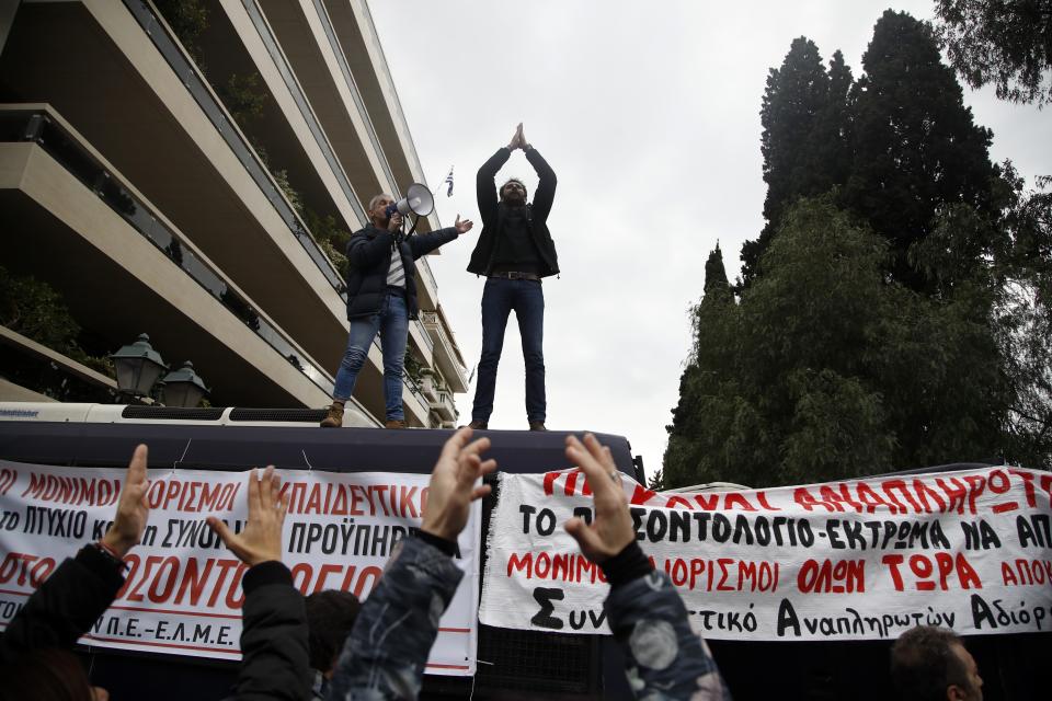 Protesters shout slogans on top of police buses during a protest near the Prime Minister's office in Athens, Friday, Jan. 11, 2019. About 1,500 people took part in the protest. Teachers' unions oppose the government's selection process for the planned hiring of 15,000 new teachers over the next three years. The banner reads ''Mass Full Time Hiring for Teachers.'' (AP Photo/Thanassis Stavrakis)