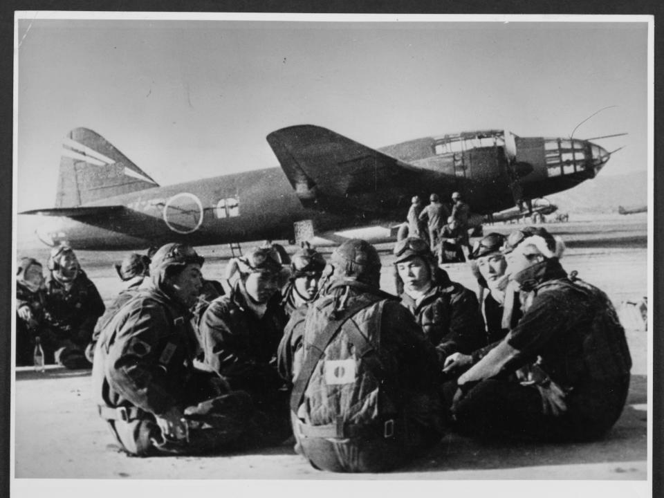 A black and white photo of US airmen sitting in front of a "Betty" bomber.