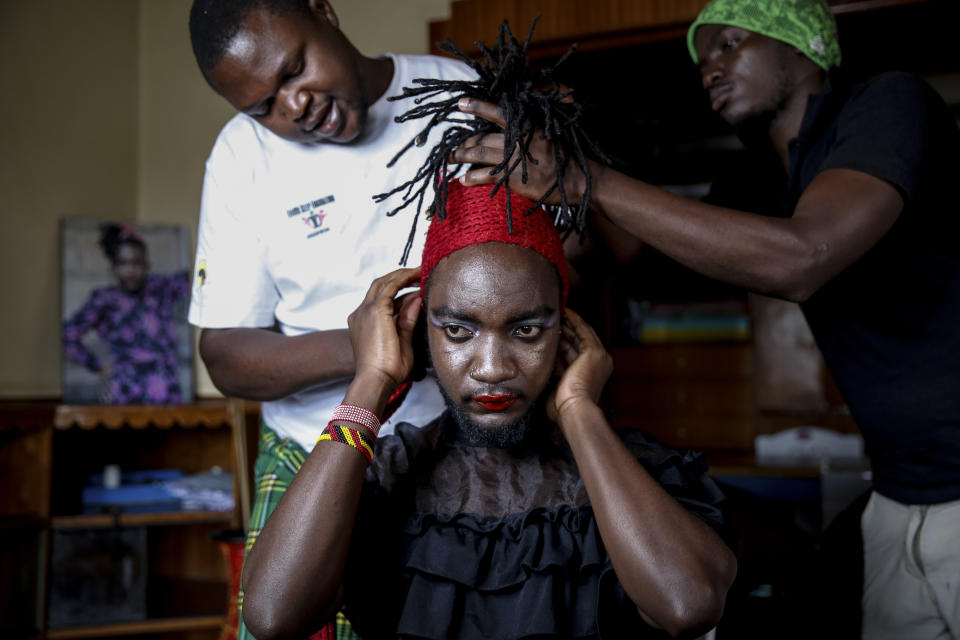 In this photo taken Thursday, June 11, 2020, Raymond Brian, center, a Ugandan refugee and a nonconforming gender person who also goes by the name of “Mother Nature” has makeup done by fellow Ugandan refugees Kasaali Brian, left, and Chris Wasswa, right, at a house that serves as a shelter for them in Nairobi, Kenya. “People feel comfortable here because it’s not far from the family setup,” Brian said. “We use family therapy to help each other overcome the trauma from our pasts." (AP Photo/Brian Inganga)