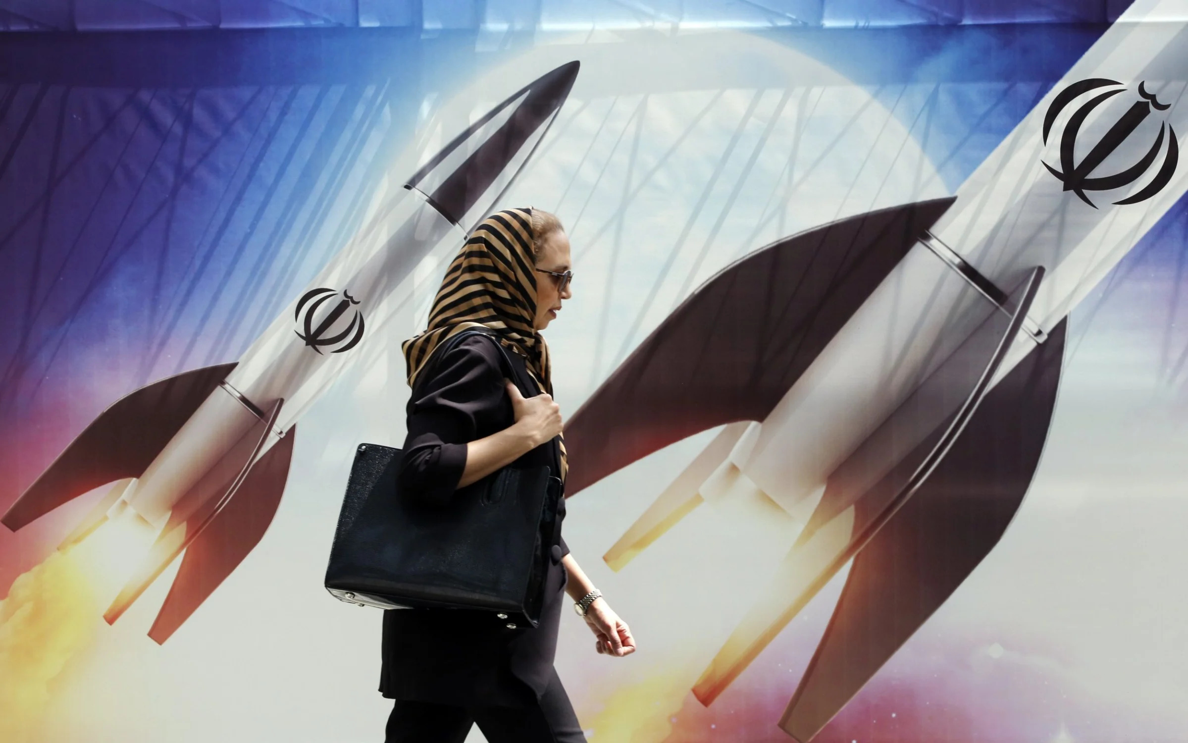 Woman walks past anti-Israel banner in Tehran