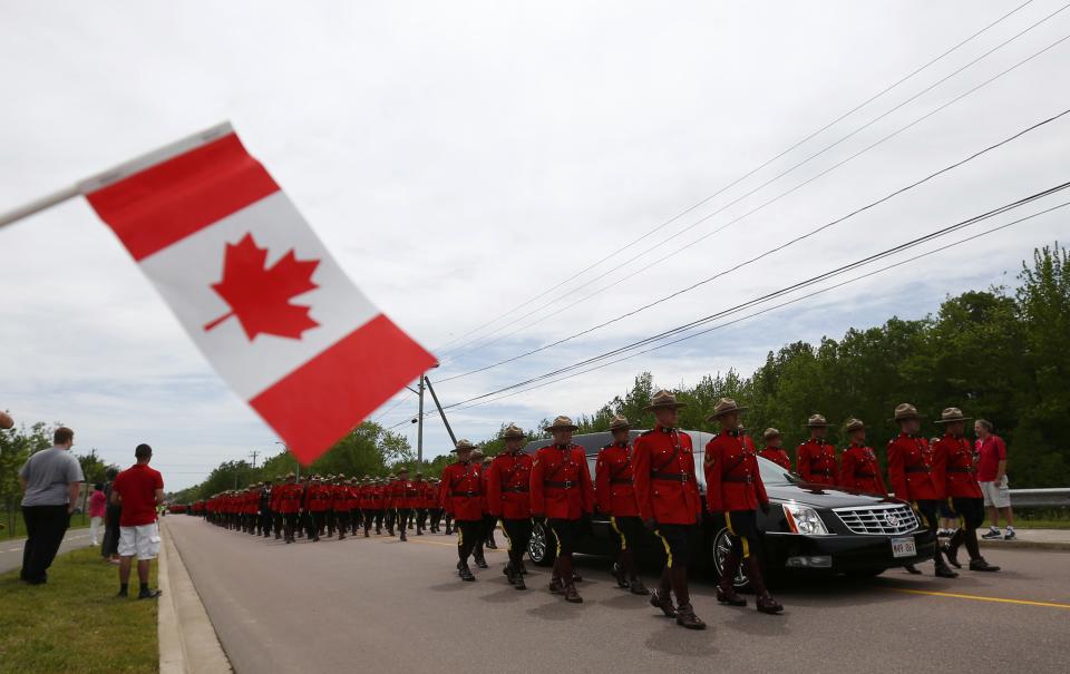 Royal Canadian Mounted Police officers march beside a hearse during a funeral procession for three fellow officers who were killed last week in Moncton