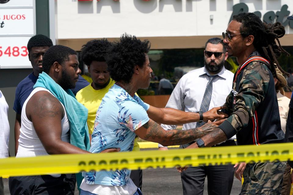 Clayton Dillard, center, is restrained by friends at the scene of a shooting outside a banquet hall in Miami, seeking information about a family member, Sunday, May 30, 2021.