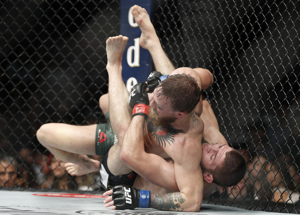 Khabib Nurmagomedov, right, takes down Conor McGregor during a lightweight title mixed martial arts bout at UFC 229 in Las Vegas, Saturday, Oct. 6, 2018. Nurmagomedov won the fight by submission during the fourth round to retain the title. (AP Photo/John Locher)