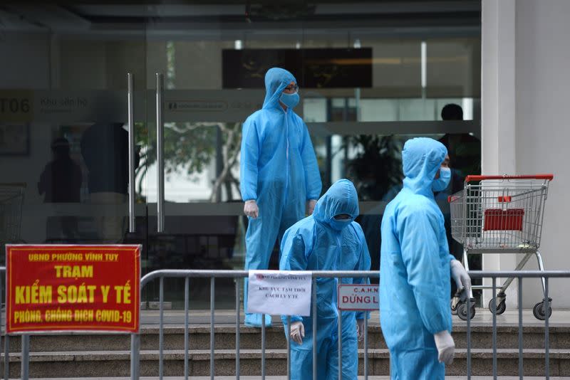 FILE PHOTO: Medical workers in protective suits stand outside a quarantined building amid the coronavirus disease outbreak in Hanoi