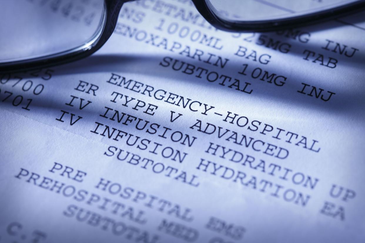 Close up of a pair of glasses on top of a hospital bill with various charges.