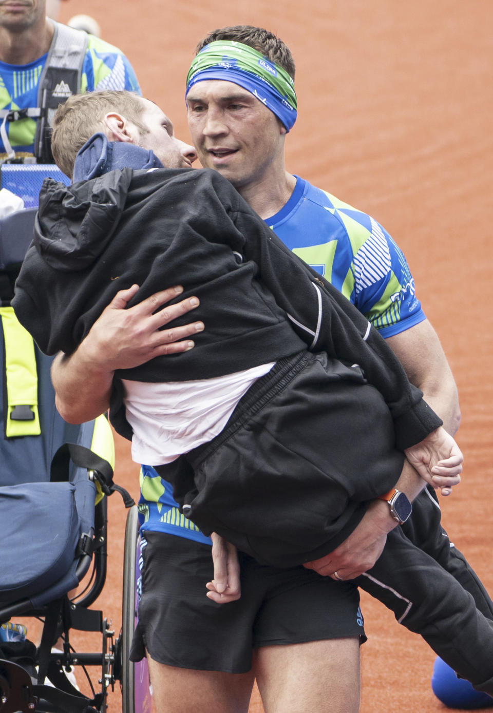 Kevin Sinfield carries Rob Burrow as he crosses the finish line of the '2023 Rob Burrow Leeds Marathon' which started and finished at Headingley Stadium, Leeds, May, 14, 2023. Rob Burrow, a former rugby star who was widely praised for his fundraising campaigns after being diagnosed with Lou Gehrig’s disease in 2019, has died. He was 41. (Danny Lawson/PA via AP)