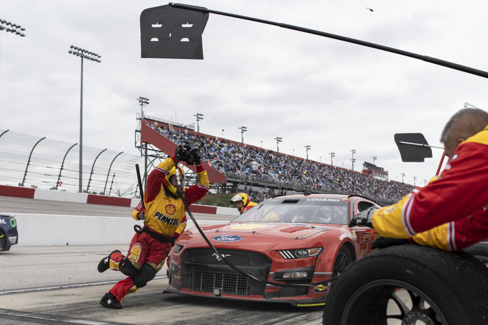 Members of Joey Logano's pit crew rush to complete a pit stop during a NASCAR Cup Series auto race at Darlington Raceway, Sunday, May 8, 2022, in Darlington, S.C. (AP Photo/Matt Kelley)