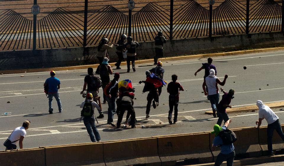 Anti-government protesters throw stones at Bolivarian National Police during clashes in Caracas, Venezuela, Saturday, March 22, 2014. Two more people were reported dead in Venezuela as a result of anti-government protests even as supporters and opponents of President Nicolas Maduro took to the streets on Saturday in new shows of force. (AP Photo/Fernando Llano)