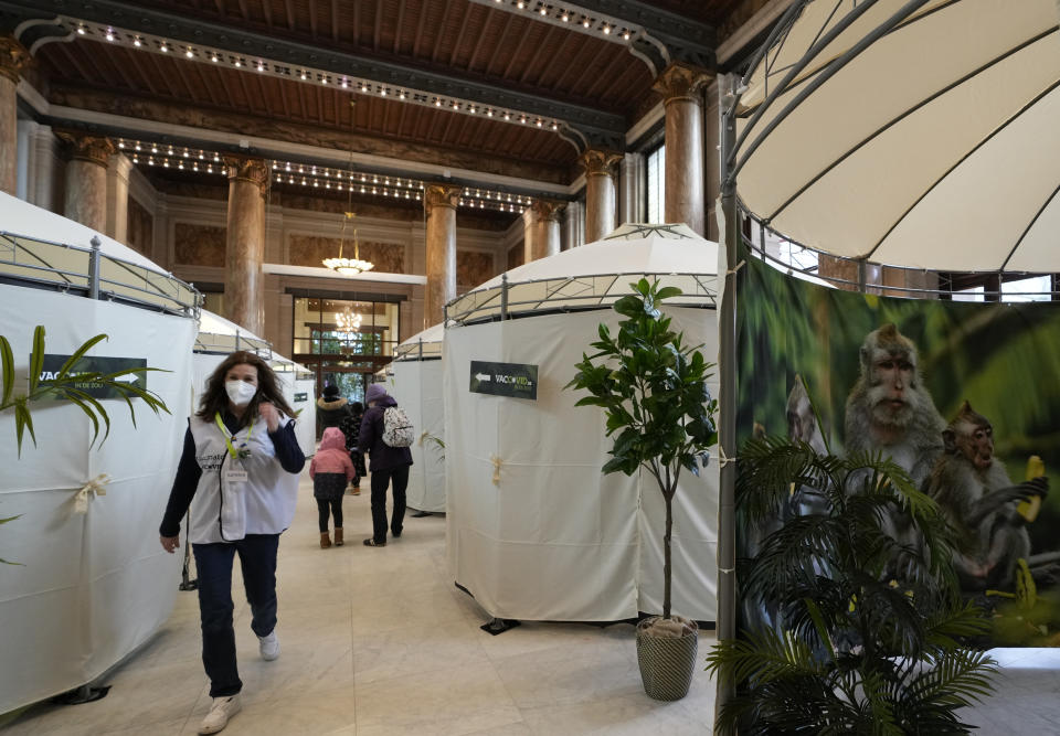 A vaccinator walks between tents where children receive a COVID-19 vaccine at the Antwerp Zoo in Antwerp, Belgium, Wednesday, Jan. 12, 2022. In an effort to make children more at ease in getting their vaccine, specially designed safari tents with photos of zoo animals have been installed to provide a more private setting with a vaccinator. Once they have received the vaccine, children and parents can stroll through the greenhouse and visit the monkey enclosure. (AP Photo/Virginia Mayo)