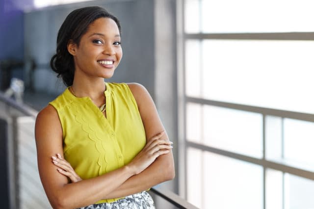 Friendly african american woman standing with arms crossed in a modern bright office