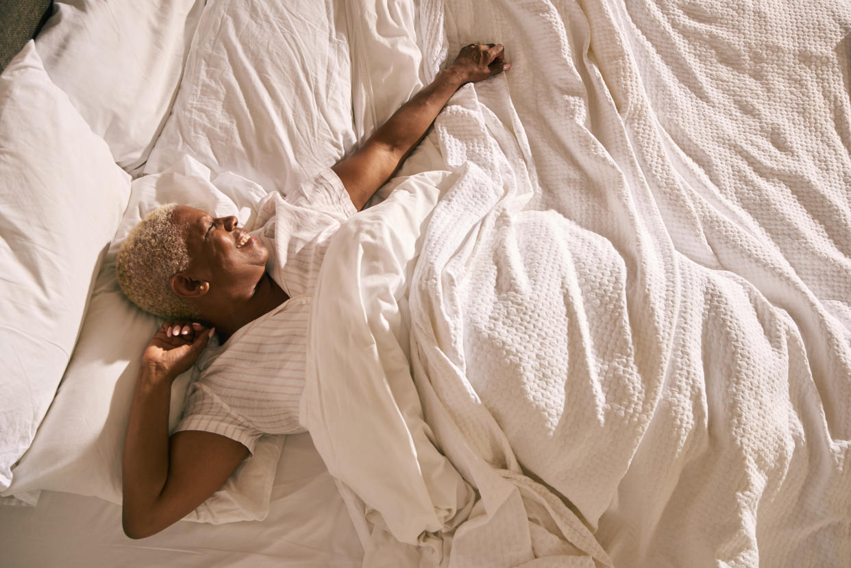 A mature woman wakes up and stretches in early morning light