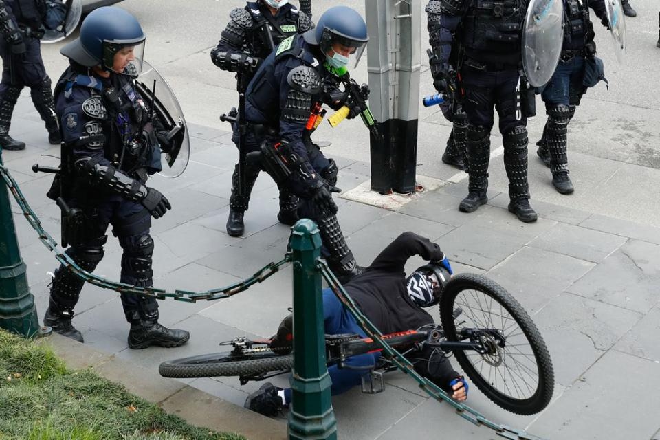 A demonstrator is handled by police officers attempting to disperse a protest against Covid-19 regulations in Melbourne on 21 September 2021 (AFP via Getty Images)