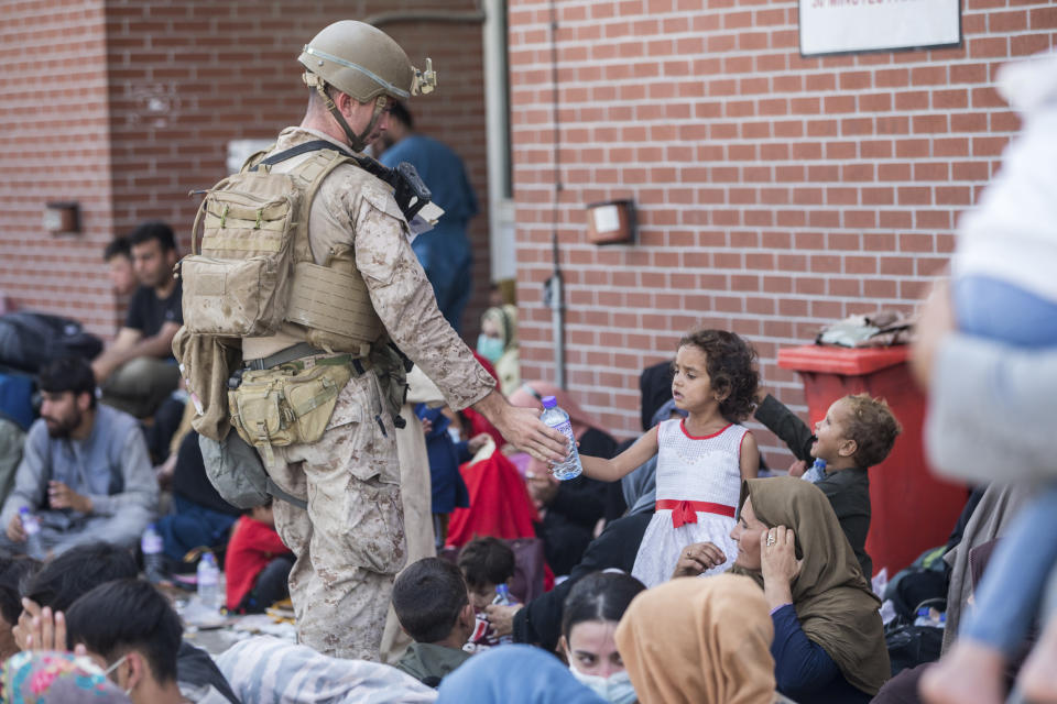 In this Aug. 21, 2021, photo provided by the U.S. Marine Corps, a Marine with Special Purpose Marine Air-Ground Task Force-Crisis Response-Central Command (SPMAGTF-CR-CC) provides fresh water to a child during an evacuation at Hamid Karzai International Airport in Kabul, Afghanistan. (Sgt. Samuel Ruiz/U.S. Marine Corps via AP)