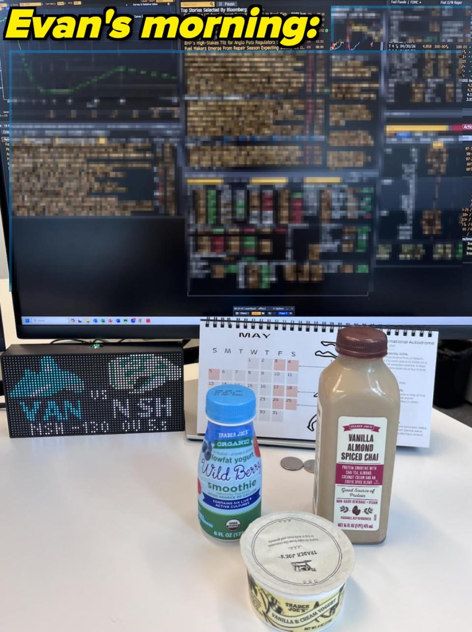 Desk with computer monitors displaying financial charts, keyboard, and breakfast items