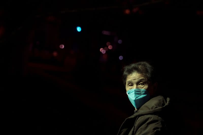 Man wearing face masks walks in a park at night in Jiujiang