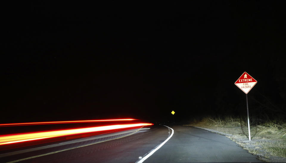 A car drives past a fire hazard sign in Waimea, Hawaii, on Thursday, Aug. 5, 2021. The region was scorched by the state's largest-ever wildfire. (AP Photo/Caleb Jones)