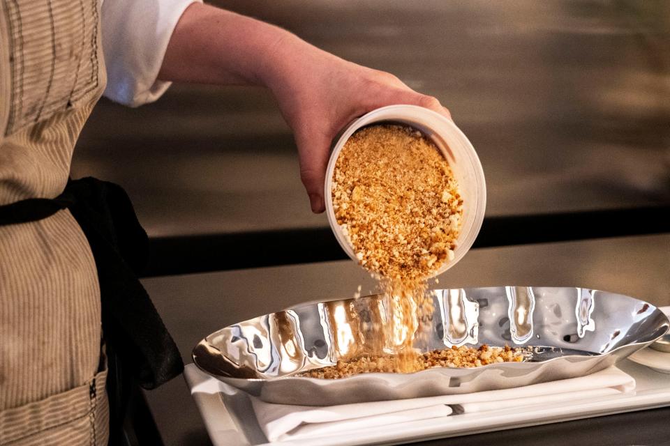 Oak Park executive pastry chef Jess Robertson pours dehydrated angel food cake pieces into an ice cream dish at Oak Park on Wednesday, Dec. 20, 2023, in Des Moines.