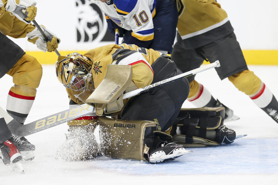 Vegas Golden Knights goaltender Logan Thompson, center bottom, makes a save against the St. Louis Blues during the first period of an NHL hockey game Monday, Dec. 4, 2023, in Las Vegas. (AP Photo/Ian Maule)