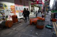 People walk past overturned rubbish bins and scattered debris following overnight clashes between protesters and police in the Mongkok area of Hong Kong on February 9, 2016