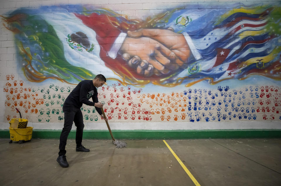 Venezuelan migrant Jonathan Colina mops the floor of a government-run shelter in Ciudad Juarez, Mexico, Sunday, Dec. 18, 2022. Texas border cities were preparing Sunday for a surge of as many as 5,000 new migrants a day across the U.S.-Mexico border as pandemic-era immigration restrictions expire this week, setting in motion plans for providing emergency housing, food and other essentials. (AP Photo/Andres Leighton)