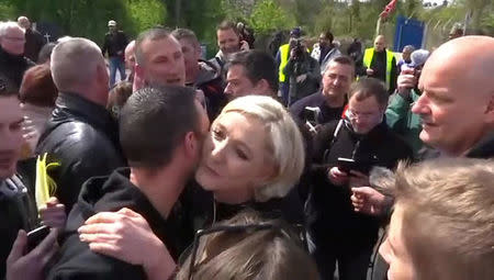 Marine Le Pen (C), French National Front (FN) political party candidate for French 2017 presidential election, kisses an employee, in this still picture taken from video, as she visits Whirlpool employees in front of the company plant in Amiens, France, April 26, 2017. BFMTV via REUTERS