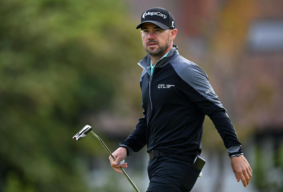 Harman walks on whilst holding a putter