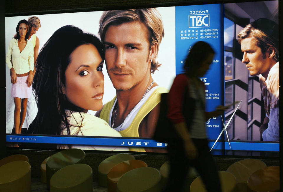 Pedestrians pass by an advertisement featuring soccer star and England Team captain David Beckham with his wife Victoria  June 19, 2003 in Tokyo, Japan. (Junko Kimura / Getty Images)