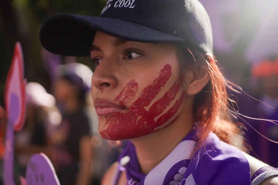 A woman with a red handprint on her face to symbolize murdered and missing woman, takes part in a march to the Zocalo to mark International Day for the Elimination of Violence against Women, in Mexico City, Saturday, Nov. 25, 2023. (AP Photo/Aurea Del Rosario)