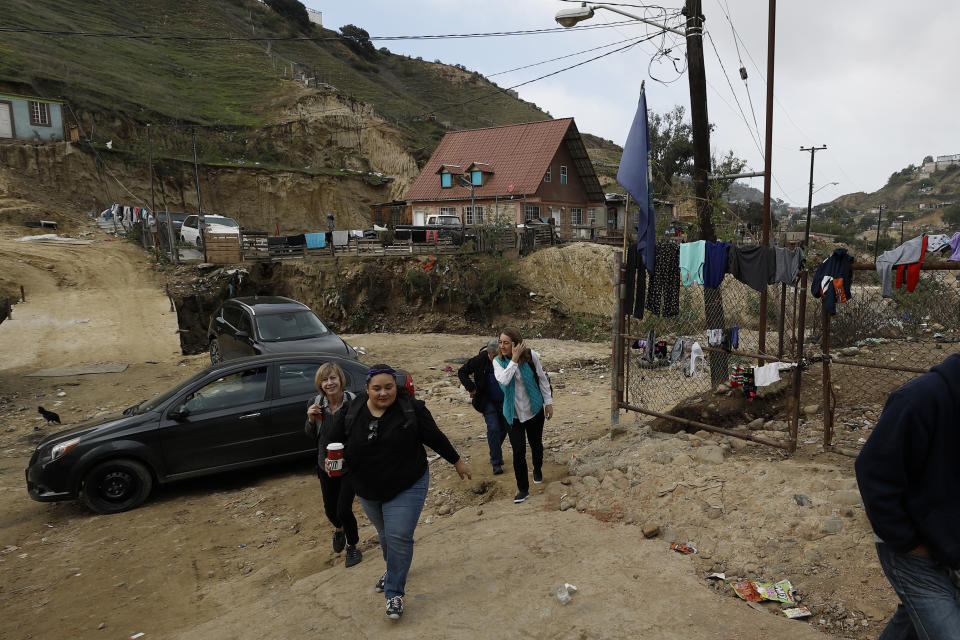 In this Dec. 14, 2019, photo, Psyche Calderon, center, leads other volunteer health care professionals on their way to a shelter for migrants in Tijuana, Mexico. In Tijuana, volunteers like Calderon have been going out to gritty, far-flung neighborhoods to set up pop-up clinics on the weekends at shelters that are rarely visited by Mexico’s public health doctors, if at all. (AP Photo/Gregory Bull)