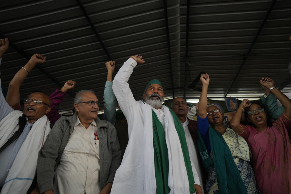 Farmer leader Rakesh Tikait , centre, and others raise slogans during a rally at Ghazipur, on the outskirts of New Delhi, India, Friday, Nov. 26, 2021. Tens of thousands of farmers rallied on Friday marking one year of their movement that forced Prime Minister Narendra Modi to withdraw three agriculture laws that feared would drastically reduce their incomes and leave them at the mercy of corporations. (AP Photo/Manish Swarup)