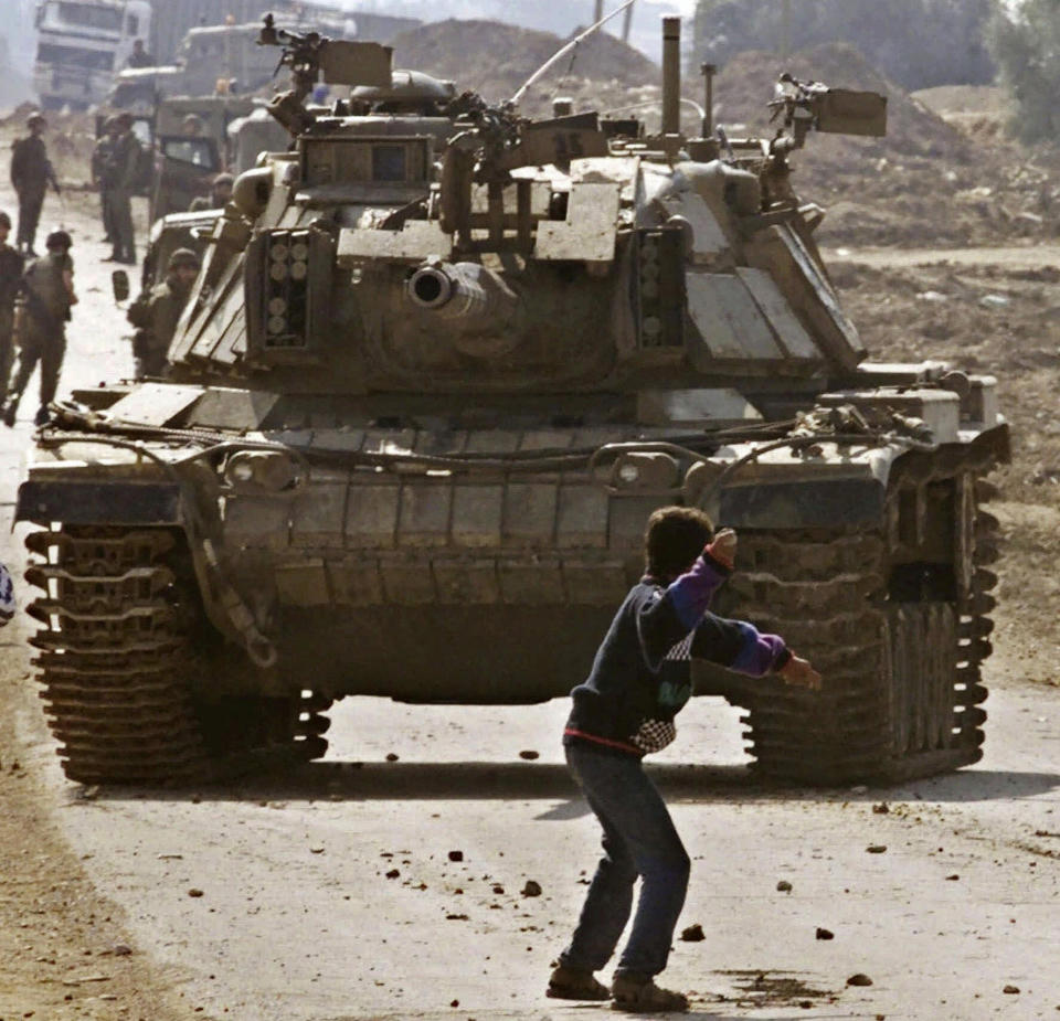 FILE - A Palestinian stone thrower faces an Israeli tank during clashes at the Karni crossing point between Israel and the Gaza Strip on the outskirts of Gaza City, Oct. 29, 2000. (AP Photo/Laurent Rebours, File)