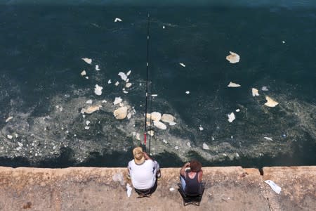 A fisherman dangles his line to catch fish in polluted water off Beirut's seaside Corniche