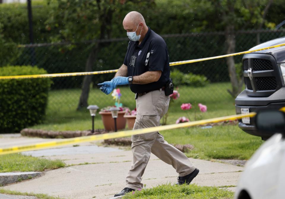 An investigator walks out of a home along Broadway Street, Sunday, June 25, 2023, in Newton, Mass. A couple celebrating their 50th wedding anniversary were stabbed to death, along with another family member, in what law enforcement officials said was probably a random attack. (Jessica Rinaldi/The Boston Globe via AP)