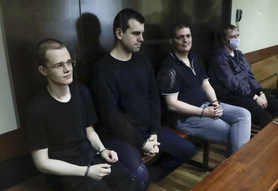 Members of the New Greatness group, who are charged with the organization of an extremist association, sit behind a glass in a courtroom prior to a court hearing in Moscow, Russia, Tuesday, July 14, 2020. Russian authorities on Tuesday demanded prison terms for three members of a youth group charged with creating an extremist organization, in a case that elicited public outraged and has been seen as politically motivated. (AP Photo/Pavel Golovkin)