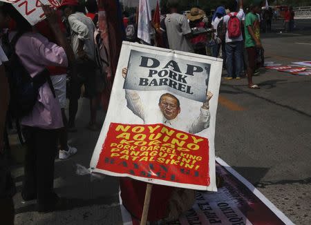 A protester holds a placard containing an image of Philippine President Benigno Aquino during a rally near Batasang Pambansa where Aquino will address the joint session of Congress and deliver his last State of the Nation address in Quezon city, Metro Manila, Philippines July 27, 2015. REUTERS/Lorgina Minguito