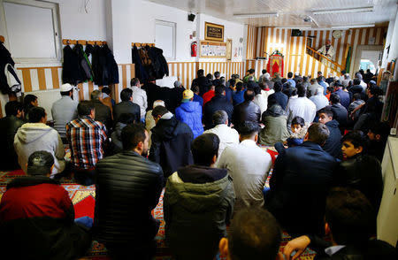 Muslims listen to a Turkish imam during Friday prayers at the Turkish Kuba Camii mosque located near a hotel housing refugees in Cologne's district of Kalk, Germany, October 14, 2016. REUTERS/Wolfgang Rattay