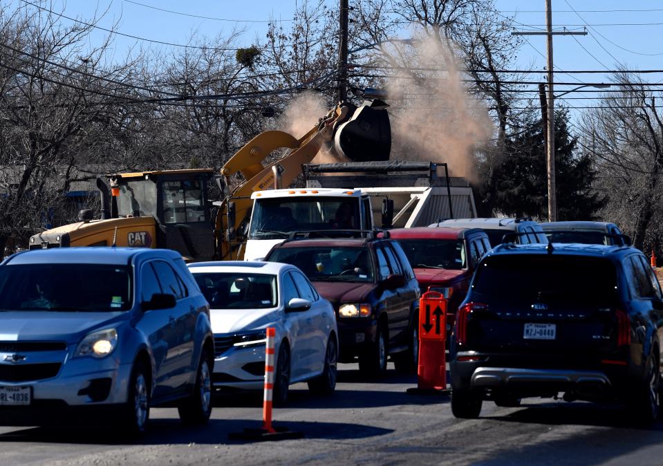 Cars wait Friday for the light to change as dirt is being dumped into a truck bed on South 27th Street.