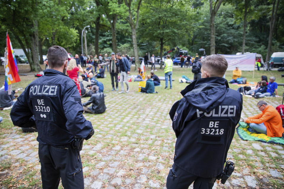 Police officers observe supporters of the initiative "Querdenken 711" in Berlin's Tiergarten not far from the Federal Chancellery, Friday, Aug. 28, 2020. Police in Berlin have requested thousands of reinforcements from other parts of Germany to cope with planned protests at the weekend by people opposed to coronavirus restrictions. (Christoph Soeder/dpa via AP)