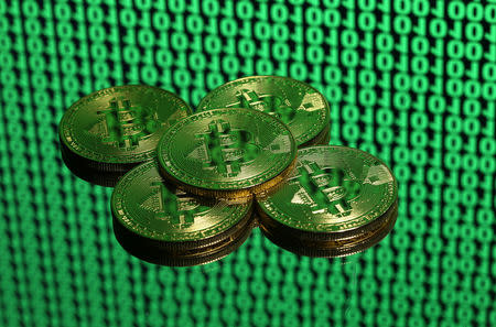 Tokens of the virtual currency Bitcoin are seen placed on a monitor that displays binary digits in this illustration picture, December 8, 2017. REUTERS/Dado Ruvic/Illustration