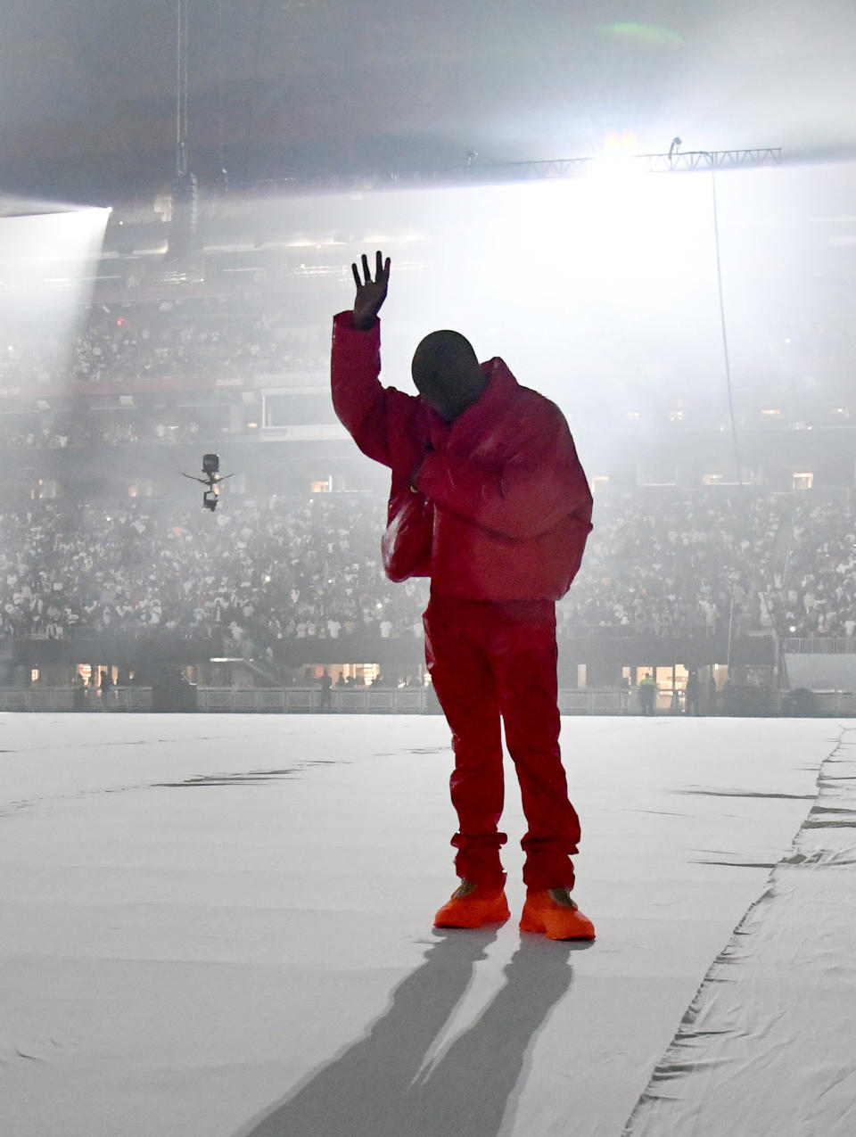 Kanye performing in a puffer jacket, matching pants and shoes, and a full face mask