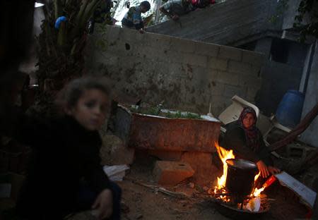 A Palestinian woman burns firewood to cook at her house in the northern Gaza Strip March 20, 2014.REUTERS/Mohammed Salem