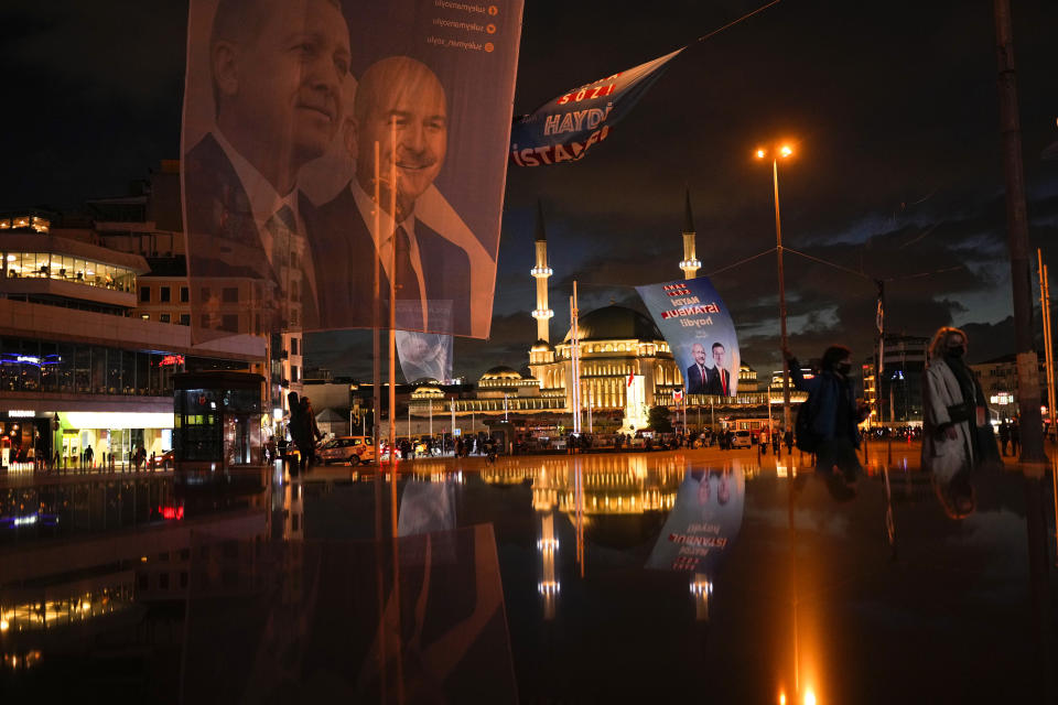 Pedestrians walk past a giant banner of Turkish President and People's Alliance's presidential candidate Recep Tayyip Erdogan, left, and Turkish CHP party leader and Nation Alliance's presidential candidate Kemal Kilicdaroglu, background right, at Taksim square in Istanbul, Turkey, Wednesday, May 10, 2023. (AP Photo/Francisco Seco)