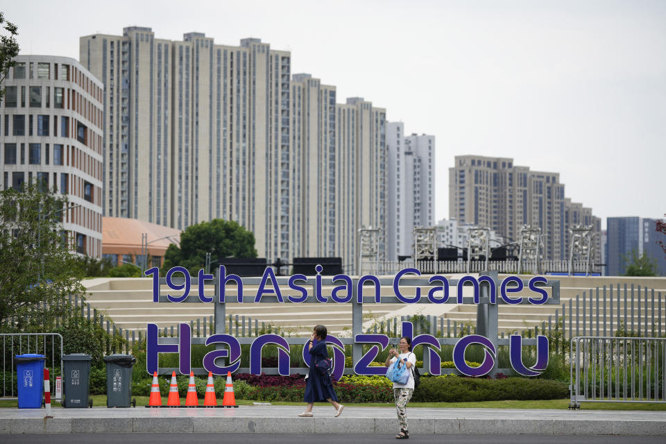 People walk past by signboard of the 19th Asian Games in Hangzhou , China, Wednesday, Sept. 20, 2023. The Asian Games are an attention grabber. For starters, they involve more participants than the Summer Olympics. Organizers say more than 12,000 will be entered as the opening ceremony takes place Saturday, Sept. 23 in the eastern Chinese city of Hangzhou. (AP Photo/Vincent Thian)